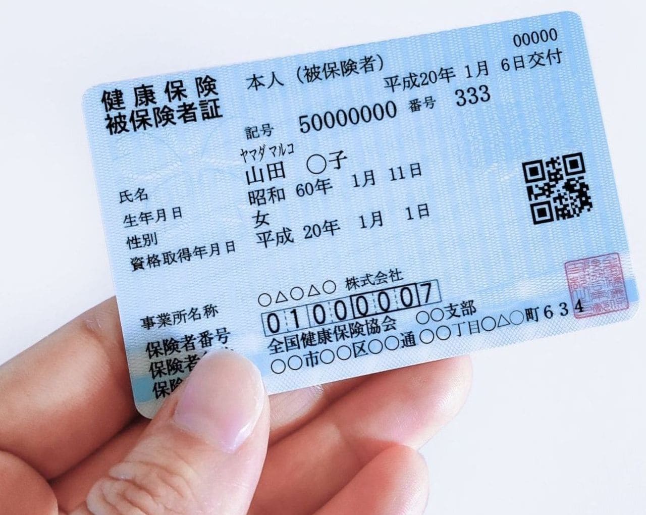 保険証を手で持っている